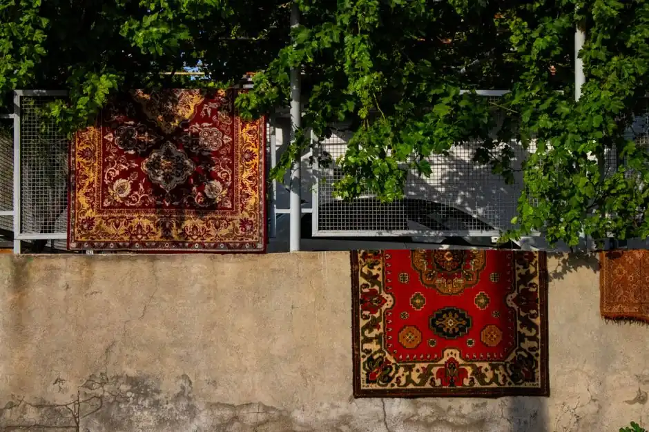Colorful oriental rugs hung outdoors to dry in a sunny Yerevan courtyard.